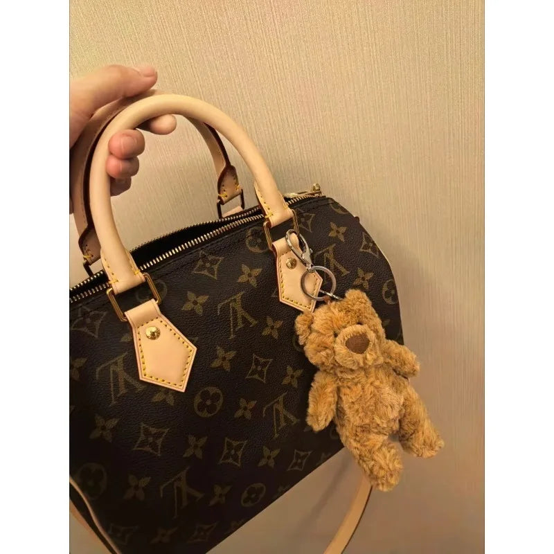 LV Handbag with a teddy bear keychain on a neutral background